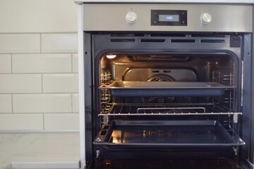 The oven door is open. The light is on inside and the oven tray are visible.