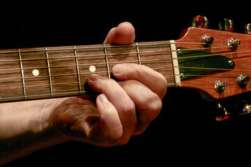 musician's fingers playing a chord on a guitar neck