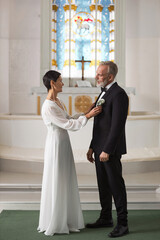 Vertical full length portrait of elegant senior couple as bride in groom in church before wedding...