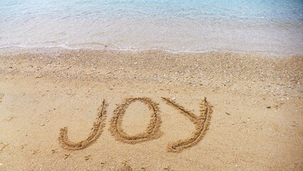 Joy - letters in sand on the beach