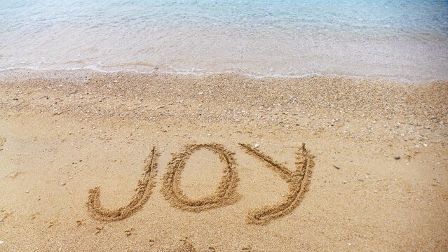 Joy - letters in sand on the beach