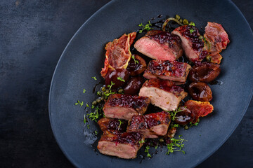 Traditional fried wild hare back filet with plums, cranberries and bacon in red wine jus served as top view on Nordic design plate with copy space © HLPhoto