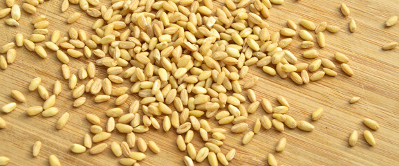 Dry wheat grain on bamboo cutting board, foot background