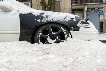 Snow-covered passenger car parked on street after snow removal, buried in snow