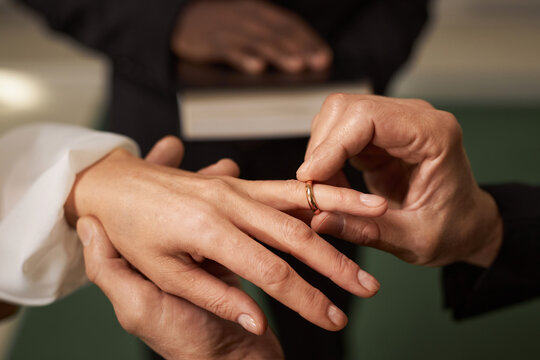Close up of senior couple exchanging rings in church on wedding day, copy space