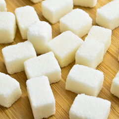 White sugar cubes on bamboo cutting board, sugar cubes texture