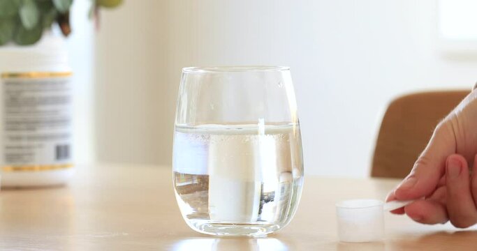 Collagen powder is poured into a glass of water and stirred with a spoon. Health