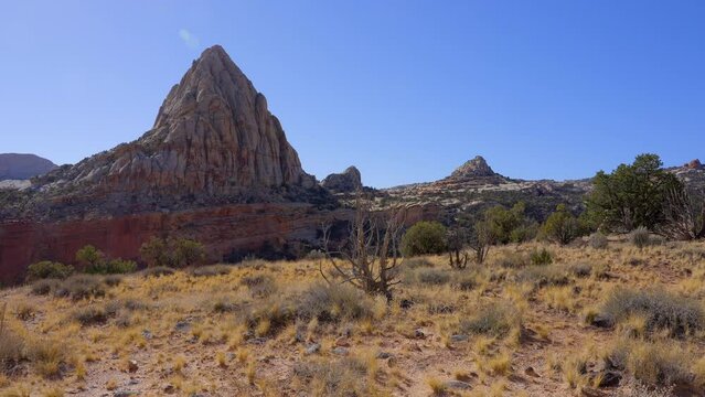 Establishing shot of mountain trail with red rocks background in Hickman Natural Bridge Trail, Capital Reef National Park, Utah, North America. Day time on October 2023. Still camera view. ProRes 422 