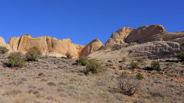 Establishing shot of mountain trail with red rocks background in Hickman Natural Bridge Trail, Capital Reef National Park, Utah, North America. Day time on October 2023. Still camera view. ProRes 422 