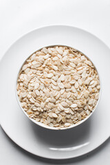 nigerian egusi seeds in a white bowl, shelled melon seeds in a bowl, nigerian melon seeds, pumpkin seeds for cooking