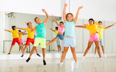 Fototapeta na wymiar Young girls and boys jumping together in dance studio.