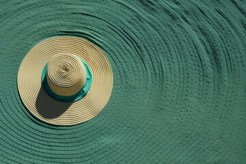 Fototapeta na wymiar a summer hat on green patterned towel. Creative design for summer vacation concept. Generative AI