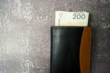 closed leather brown and black wallet filled with 200 zloty bills on a gray background. view from above. copy space. Polish economy