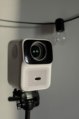 a white movie projector on
 on a tripod against a white wall
