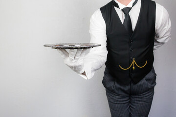 Portrait of Butler or Waiter in Black Vest or Waistcoat Holding Silver Serving Tray. Concept of Service Industry and Professional Hospitality.