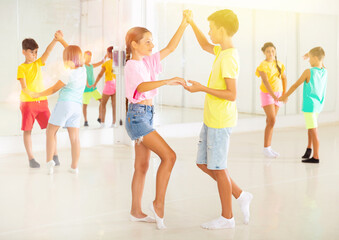 Happy boys and girls enjoying active dance in studio