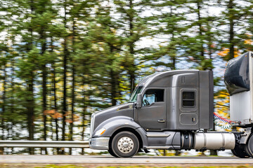Profile of bonnet gray long hauler big rig semi truck tractor with dry van semi trailer running on...