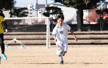 サッカーの試合をする小学生の男の子