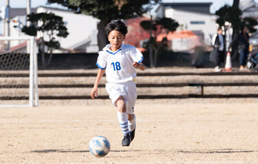 サッカーの試合をする小学生の男の子