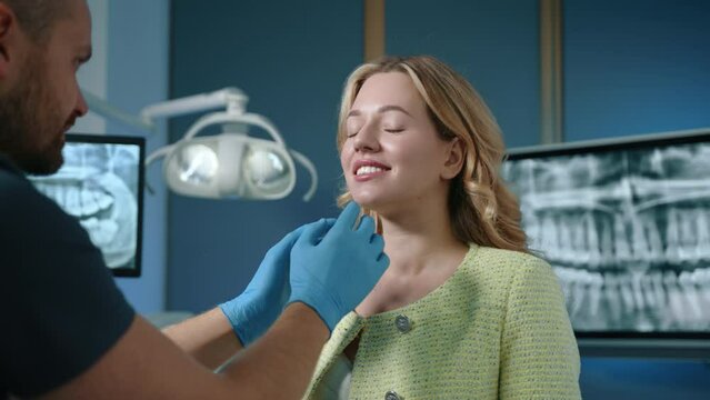 Dental expert in latex gloves checking the alignment of the teeth and the way they fit together of cheerful attractive woman in fully equipped office. High quality 4k footage