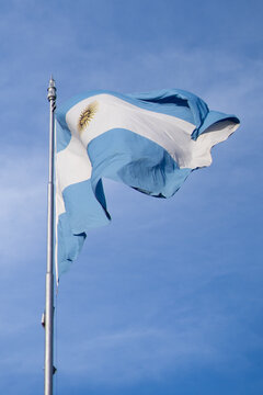 Bandera argentina flameando en mastil, delante de un cielo azul