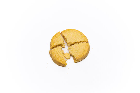 Crumbled shortbread cookie, split into four pieces,  against a white background