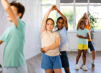 In fitness club, African boy became couple with European girl and trains to dance to rhythm of Latin music. Classes for children workout in mini group gym