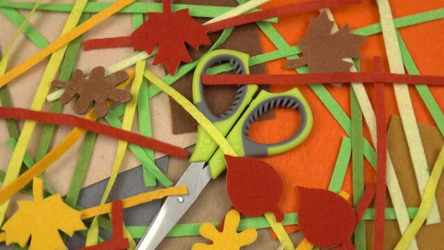 Pieces of multi-colored felt textile, thin strips of felt, felt decorative elements and scissors, materials for needlework and creativity, background
