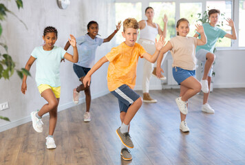 Positive boy exercising in group of classmates during dance class at dance studio