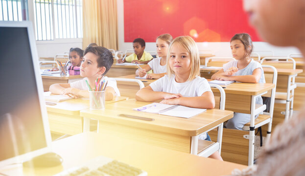 Portrait of diligent towheaded preteen girl looking at camera during lesson in primary school