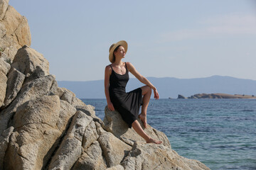 Fashion outdoor portrait of female model in midi black camisole dress on the beach, summer vacation concept