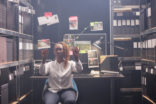 Private detective using ar for solving crime case in police office room. African american woman investigator searching insight and making hands gestures while working in augmented reality