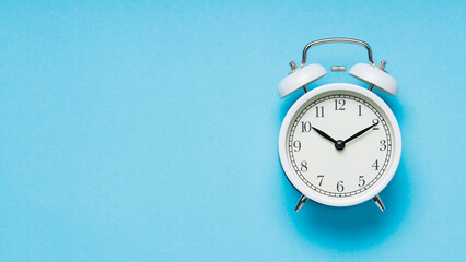 White Alarm Clock on Blue Background, Time Concept, Copy Space