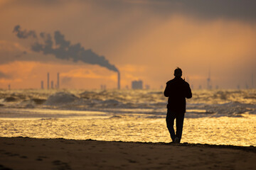 A silhouette of an old man walking on the coastline of the North Sea during the sunset near The Hague, Netherlands