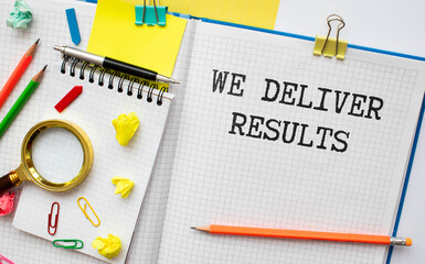 WE DELIVER RESULTS text on notebook with pen on a chart background
