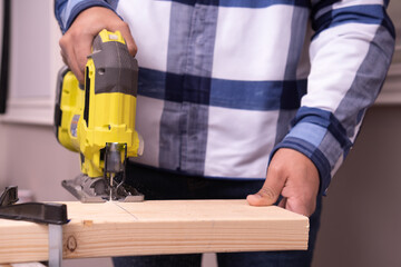 Unrecognizable man cutting a lumber with a green jig saw