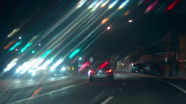 Night traffic on winding Pacific Coast Highway from Malibu to Los Angeles, POV, light streaks effect, slow motion.
