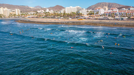 Aerial photo from drone to de surfers in the ocean beachs Adeje Playa de las Americas, Playa Honda In the background Tenerife at sunset. Tenerife, Canary islands, Spain © Sandis