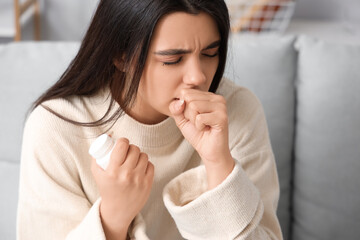 Sick coughing woman with pills at home