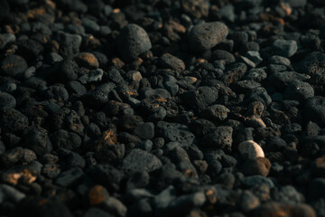 Black volcanic rocks, porous stones on a beach, pebbles,