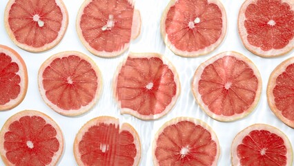 Slice of grapefruit underwater or in water with splashing and droplet top view flat lay on white background.