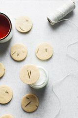 Top view of rosemary sugar cookies on a parchment lined baking sheet, baked rosemary cookie on a white background, process of making rosemary sugar cookies