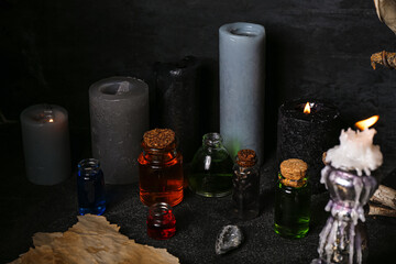 Witch's magic attributes with candles and bottles of poison on dark table