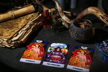 Witch's magic attributes with book and tarot cards on dark table, closeup