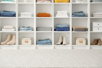 White shelving unit with stacks of different clothes and decor