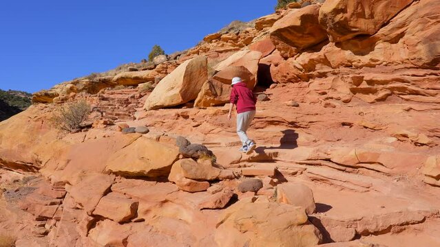 Establishing shot of female tourist at mountains in Hickman Natural Bridge Trail, Capital Reef National Park, Utah, North America. ProRes 422 HQ.
