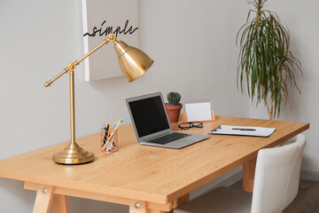 Modern workplace with laptop and lamp in room