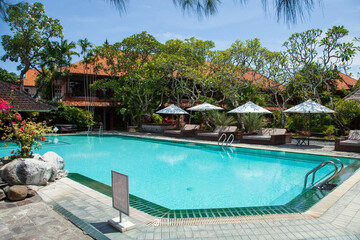 Typical Balinese swimming pool at a resort in Sanur, Bali with traditional buildings.