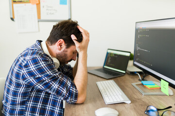 Stressed upset programmer having problems developing new software and looking worried because of...