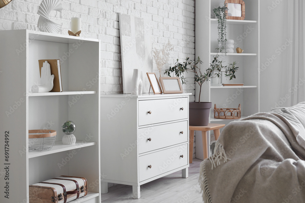 Poster interior of light living room with commode and shelf units